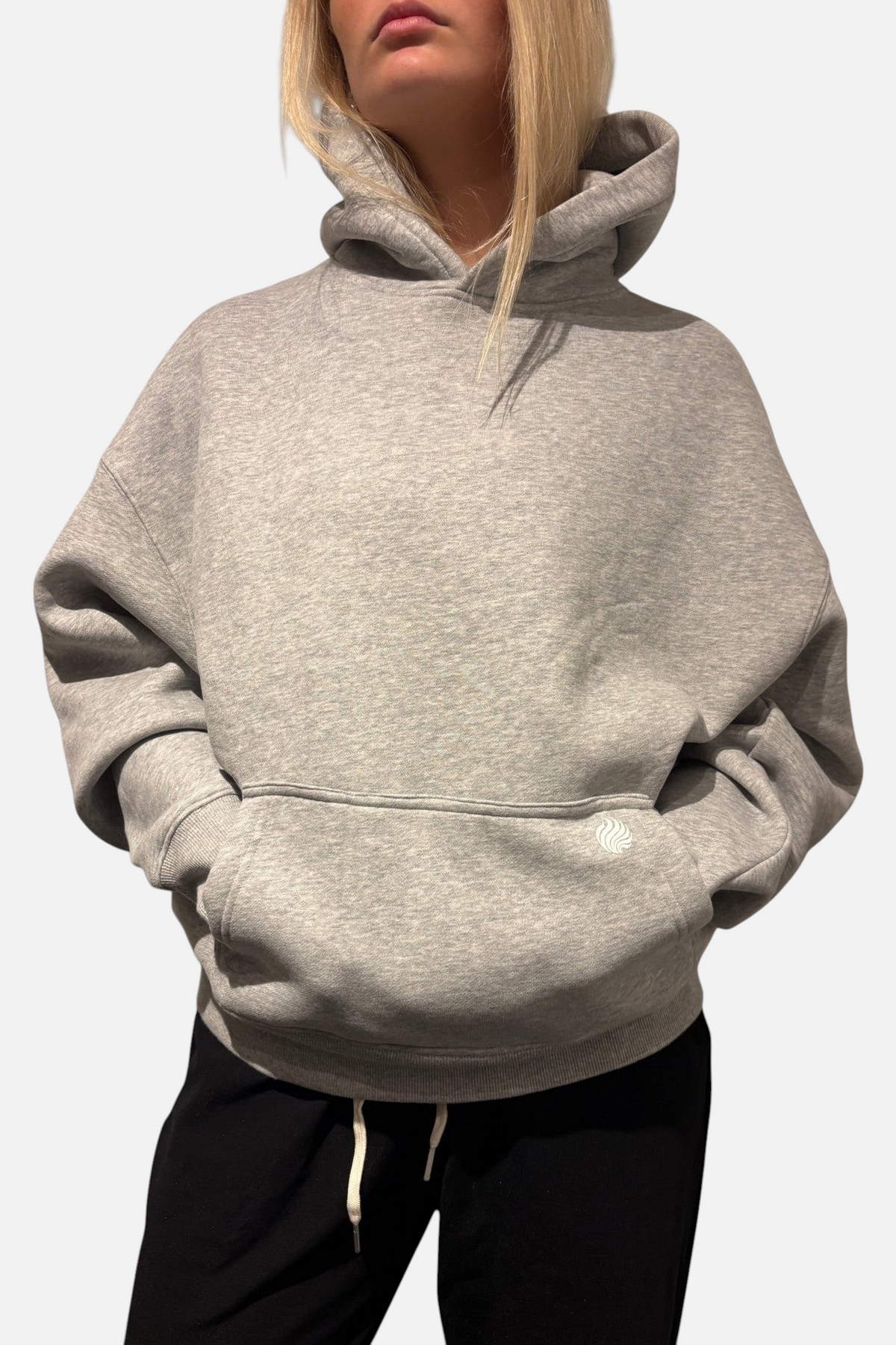 noora Soft Hoodie i grå borstad fleece med boxig passform, huva och framficka på en modell.